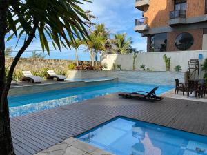 einen Pool mit einer Holzterrasse neben einem Gebäude in der Unterkunft Condomínio MANDAI Apto 305 B Lateral em frente ao mar in Cabo Frio