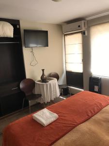 a room with a bed and a table and a tv at Edificio Terravina in Tarija