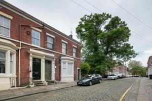 a car parked on a street next to a brick building at King Size City Centre En Suite Room with Parking in Preston