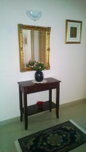 een tafel met een spiegel en een vaas met bloemen erop bij Casa Vacanza Margherita in Matera