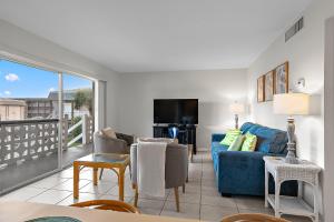 a living room with a blue couch and a balcony at Cocoa Beach Condo in Cocoa Beach