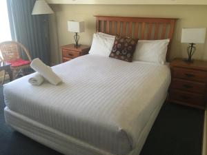 a bed with a white bedspread and pillows at Aberdeen Motor Inn in Geelong