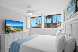 a white bedroom with a bed and a ceiling fan at Kanai a Nalu 314 - Newly Renovated, Oceanfront, AC in Wailuku +92 photos