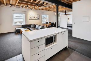 a living room with a white kitchen with a couch at Gibson Mill waterfront warehouse apartment - 101 in Hobart