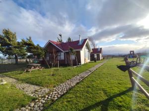 a house with a fence in front of a yard at Cabañas Terravento in Puerto Natales