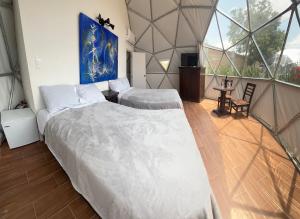 two beds in a room with a large window at Glamping Cholula in Cholula