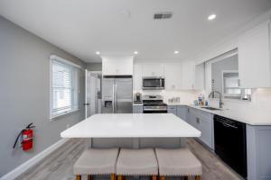 a white kitchen with a large white counter top at A Shore Thing - Spacious House w Large Deck, BBQ, Linens & Pet Friendly in North Cape May