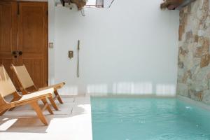 Habitación con piscina y 2 sillas en Brand New Designer 1BR Villa, en Canggu