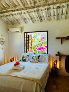 a bedroom with a large white bed with flowers on it at Pousada Tangerina in Icaraí