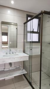 a bathroom with a sink and a mirror at Apartamento Tulum Bertioga in Bertioga