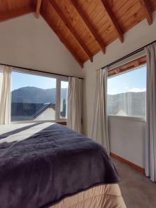 une chambre avec un grand lit et de grandes fenêtres dans l'établissement Cabaña - San Martin de los Andes, à San Martín de los Andes