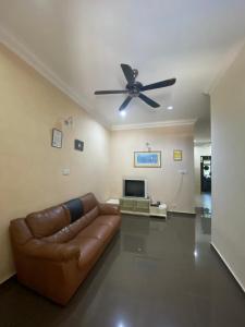 a living room with a couch and a ceiling fan at Homestay Tok Ma 1 Alur Tuman Marang in Marang