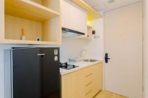una cucina con frigorifero nero e lavandino di Simply Look and Cozy Studio Tokyo Riverside PIK 2 Apartment By Travelio a Rawalembang