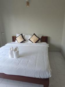 a white bed with two white shoes on it at Champa House in Vang Vieng
