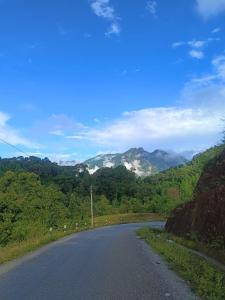 an empty road with trees and mountains in the background at Champa House in Vang Vieng
