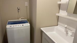 a small white bathroom with a sink and a washing machine at Naha airport hotel in Takara