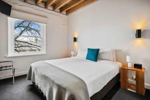 a bedroom with a large white bed with a window at Gibson Mill waterfront warehouse apartment - 201 in Hobart