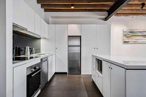 a kitchen with white cabinets and a black refrigerator at Gibson Mill waterfront warehouse apartment - 201 in Hobart +22 photos
