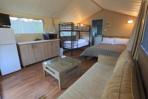 een woonkamer met een bed en een bank in een tent bij NRMA Myall Shores Holiday Park in Bulahdelah