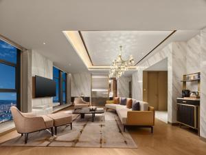 een woonkamer met een bank, stoelen en een tv bij Hilton Lanzhou City Center in Lanzhou