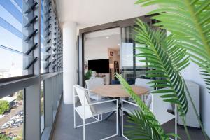 a balcony with a wooden table and white chairs at Modern Splendour, Macquarie Park I90 in Sydney