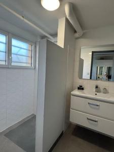 a white bathroom with a sink and a mirror at Le Phare in Agon Coutainville