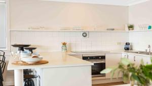 a white kitchen with a counter with dishes on it at Absolute Beachfront Beauty - Pearl Beach in Pearl Beach