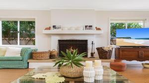 a living room with a table and a piano at Absolute Beachfront Beauty - Pearl Beach in Pearl Beach