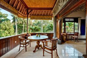 a room with a table and chairs on a porch at Fullara 1 BR Suite With Rice Field View ZN240 in Ubud
