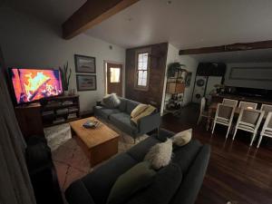 ein Wohnzimmer mit zwei Sofas und einem Fernseher in der Unterkunft Base Camp Cottage in Taupo