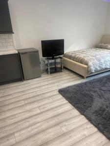 a bedroom with a bed and a flat screen tv at Lovely Modern studio flat with jacuzzi bath free parking in Stanwell