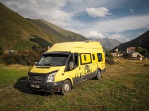 a yellow van parked in a field with mountains at best camper van in tbilisi in Tbilisi City
