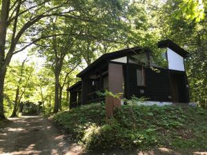 eine schwarze Hütte im Wald mit einem Feldweg in der Unterkunft Towada City Utarube Campsite - Vacation STAY 00407v in Utarube