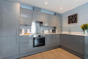 a kitchen with stainless steel appliances and gray cabinets at Elliot Oliver - Beautiful Two Bedroom Apartment With Parking in The Docks in Gloucester