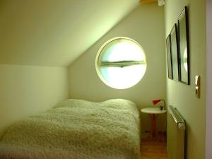 a small bedroom with a bed and a round window at Ferienhaus Kastaniengrün in Worpswede +4 photos