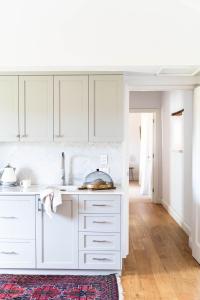 a white kitchen with white cabinets and a sink at Alkina Old Quarter Luxury Accommodation in Greenock +14 photos