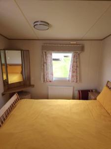 a bedroom with a large bed and a window at The Pearl - Deluxe Access Caravan in Skegness +18 photos