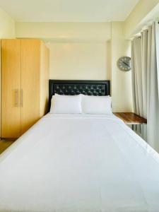 - une chambre avec un grand lit blanc et une horloge dans l'établissement 19 Cityscape Views, à Cari Mayor