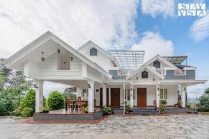 a white house with a porch at StayVista at Titha Villa in Santhanpara
