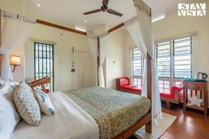 a bedroom with a bed and two red chairs at StayVista at Titha Villa in Santhanpara +26 photos