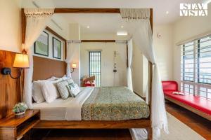 a bedroom with a canopy bed and a red couch at StayVista at Titha Villa in Santhanpara