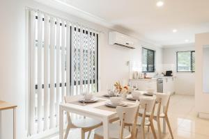 a white dining room with a white table and chairs at Smart Suites Self Check-in Apartments - Rocklea Station S in Brisbane