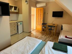 a room with a bed and a kitchen with a table at Petöfi Vendégház in Eger