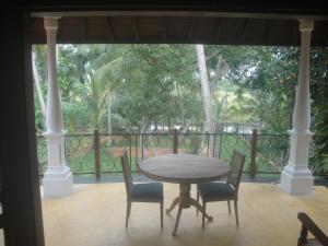 una mesa y sillas en un porche con vistas a los árboles en Priyanka Villa, en Bentota