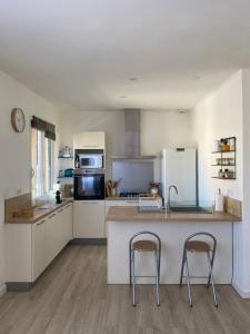 a kitchen with a counter and two bar stools at Au bord de la Camargue in Aubord