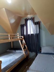 two bunk beds in a room with a roof at The Coziest Cabin by Grace in Tuding