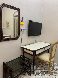 a room with a table and a tv and a mirror at Arau Heritage Home in Arau
