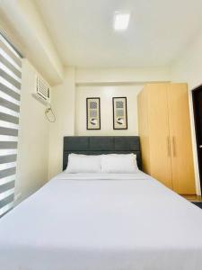 un lit blanc dans une chambre avec deux tableaux au mur dans l'établissement 20 Pool View Studio Bliss, à Cari Mayor 10 autres photos