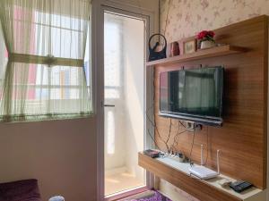 a living room with a tv and a window at Modern Look and Comfortable 2BR Green Pramuka City Apartment By Travelio in Jakarta