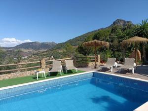 a swimming pool with chairs and a table next to a mountain at Villa Jael in El Gastor